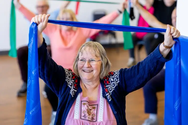Mature female exercising as part of a group session with a resistance band