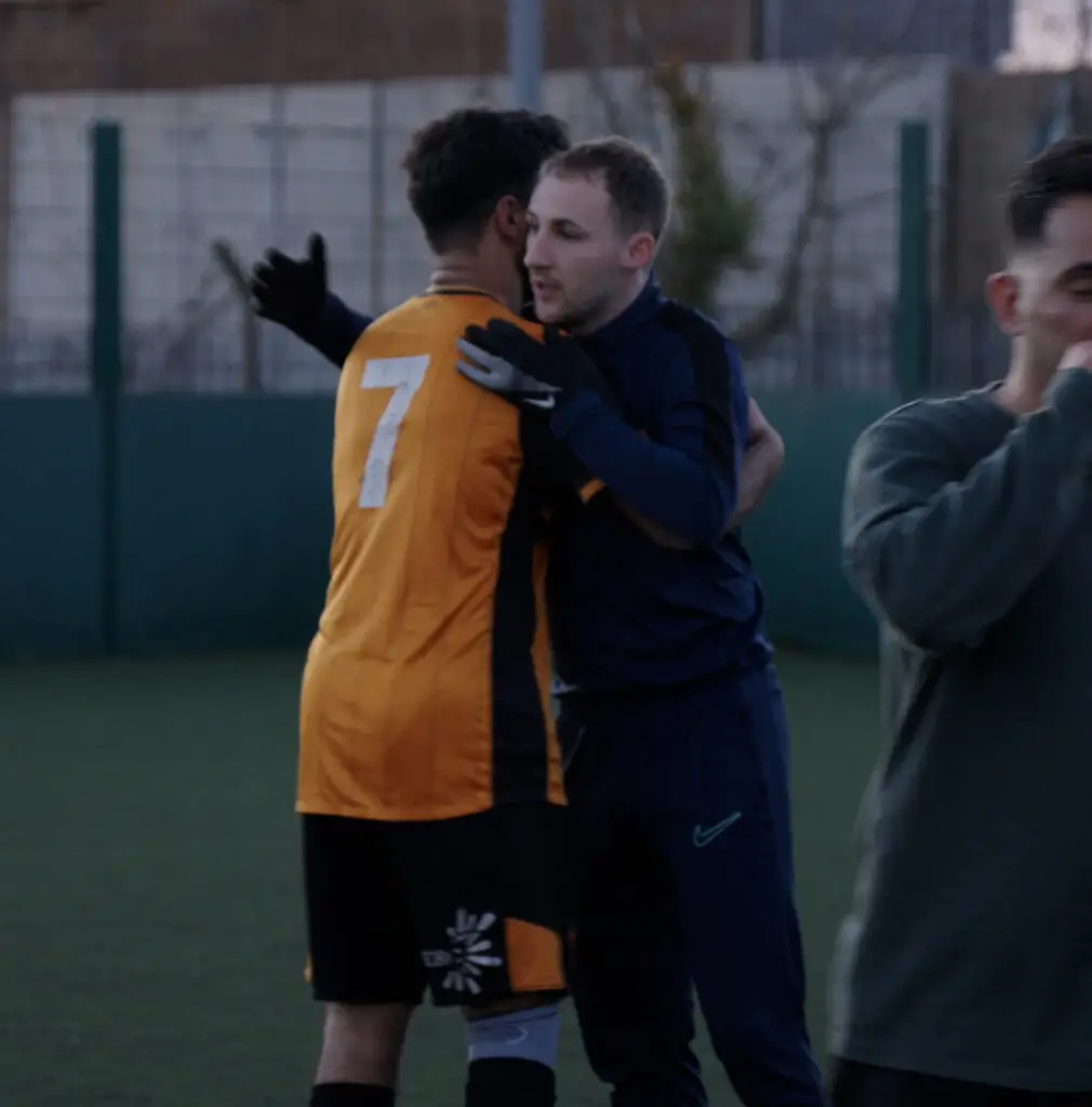 Coach Dan Richardson hugging a football player during a match