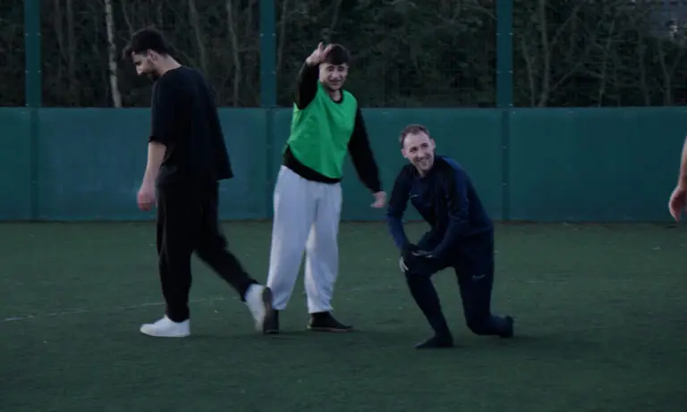Coach Dan Richardson smiling whilst playing football with his session participants