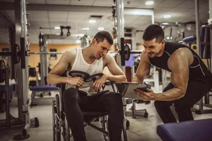 Personal Trainer helping patient in wheelchair in the gym