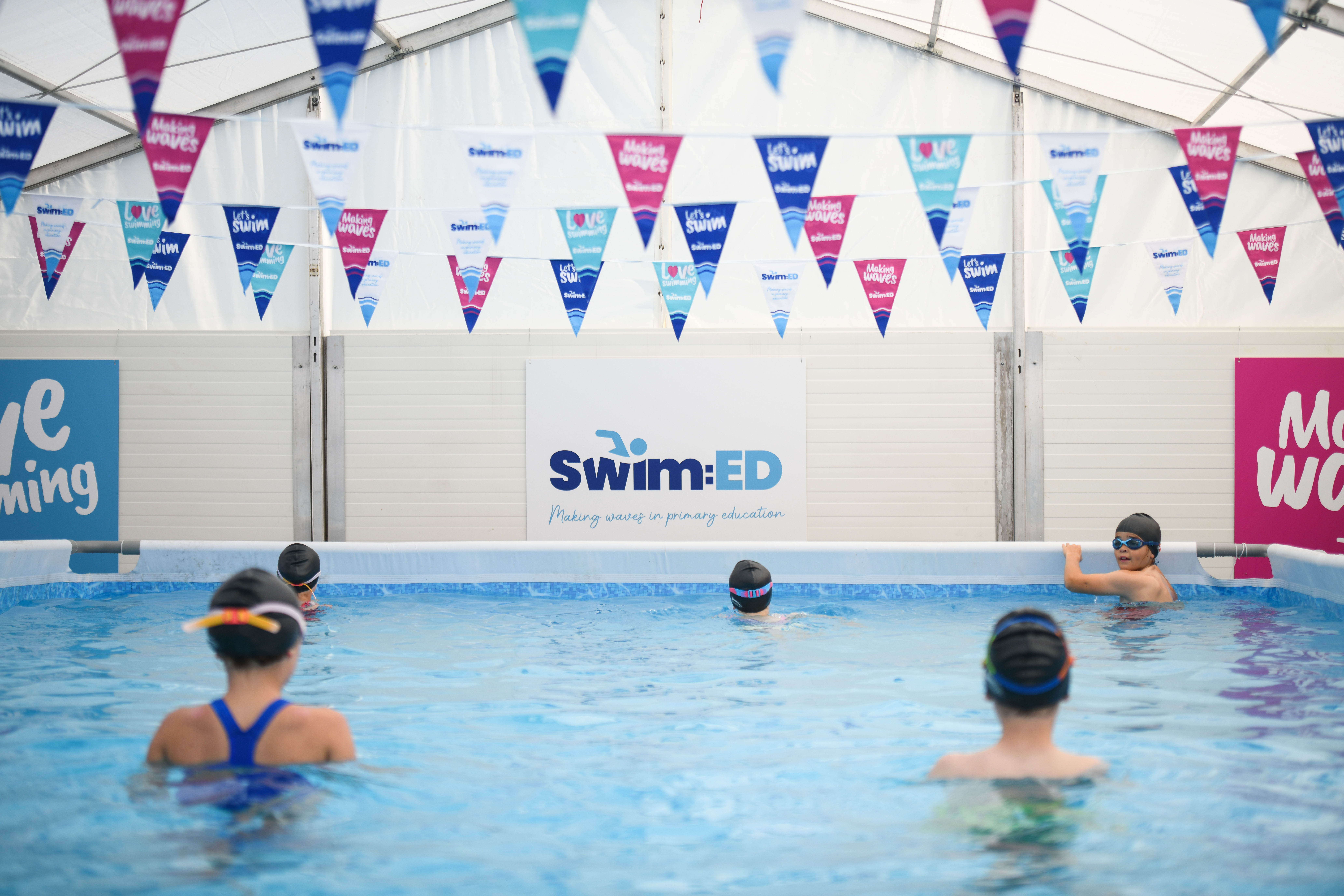 Children in pop up swimming pool with Swim:ED branding