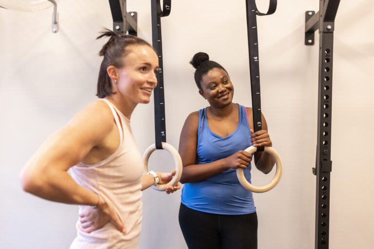Fitness trainer with a woman in gym. Personal trainer with a female standing in fitness studio.