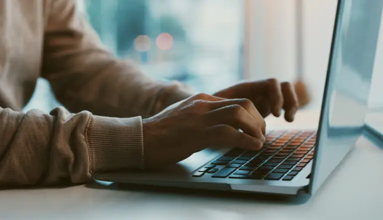 Person's hands typing on a laptop