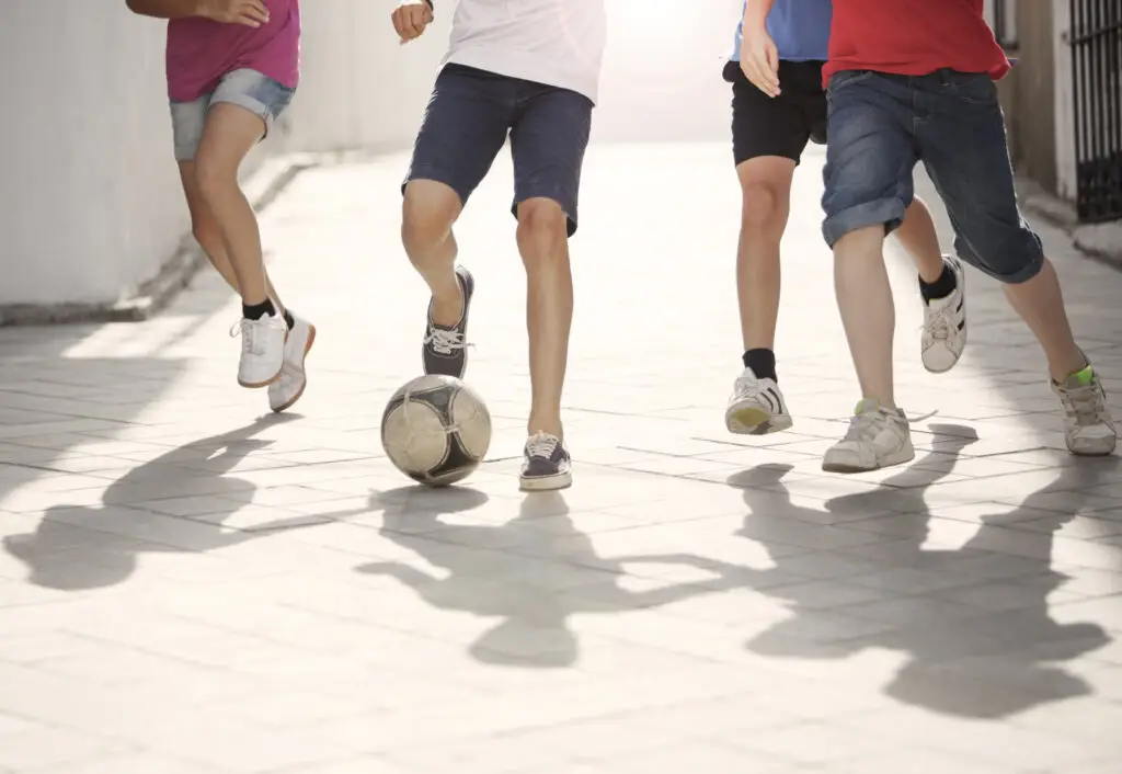 Four children playing football in the street