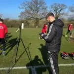 Oxford Brookes University student Keiran on a work placement monitoring data by the side of a football pitch as the team trains