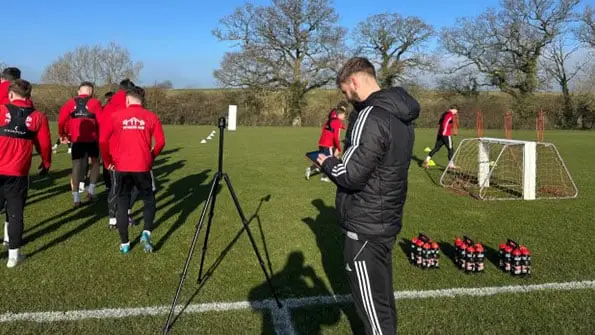 Oxford Brookes University student Keiran on a work placement monitoring data by the side of a football pitch as the team trains